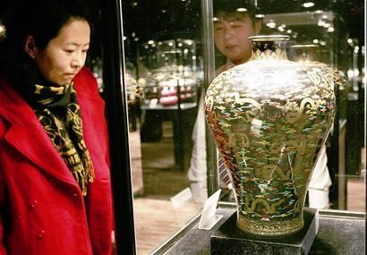 图为观众在欣赏预展的拍卖品“乌金釉堆彩描金云龙纹梅瓶”。