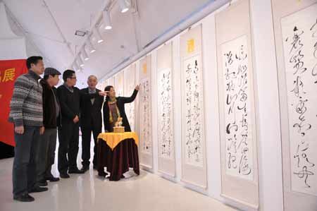 图为杨希仁(右二)与前来参观的书法爱好者一同观看玉雕“圣土望君归”和<望君归礼赞>书法狂草书法作品。