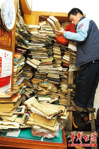 2月14日，苏利群站在楼梯上，整理墙角大书架上的藏书，这些只是他收藏的一部分书籍，还有更珍贵的一些明清和民国时的旧书，他都收在木箱里。(记者 王?鹰 摄)