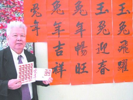 书法老师谭超常为加拿大邮务公司所书写的兔年邮票题字，其手上所持是今年印有他的书法的“兔年”邮票及首日封。(加拿大《明报》/孔伟民 摄) 