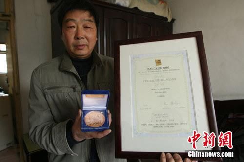 苗向光展示他获得的集邮奖状、奖牌。孙翔鸣 摄