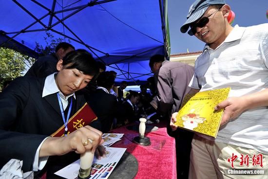图为西藏自治区邮政公司的工作人员正在给《西藏和平解放60周年》纪念封上加盖邮戳。李林 摄  