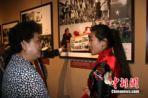 图为中国传媒大学藏族女大学生丹增敏吉为陈至立讲述参展图片背景。肖媛媛 摄