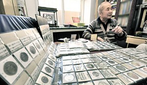 图为穆安华老人向记者介绍他收集的硬币