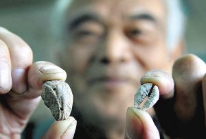 卫国定老人拿着一枚陶币（左）和贝币（右）。（摄影）邱孝威 
