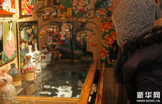 一名顾客在北京烟袋斜街的“丰年陶坊”观看古瓷片饰品