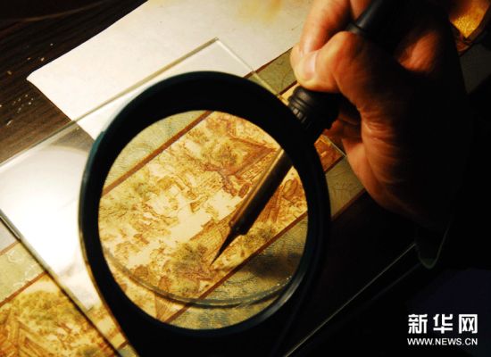 谢仁山对袖珍彩墨烙画《清明上河图》进行最后的完善工作