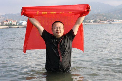 自称表演爱国行为艺术的雪马身批红布站立海水中，给人以炒作之嫌