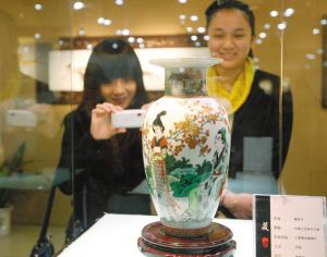 观众正在欣赏当代“古彩大王”、中国工艺美术大师戴荣华的《人面桃花相映红》古彩瓷瓶。　