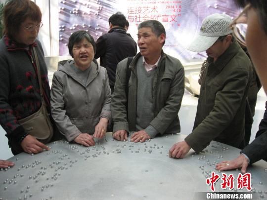 近百位视觉残障人士23日走进上海宝山国际民间艺术博览馆，参观“连接艺术与社会的‘盲文’??李秀勤雕塑二十年”展。图为盲人们在聆听博览馆工作人员讲解的同时，用手指细细地触摸展品，以触觉感受雕塑艺术的魅力。　于俊 摄　摄