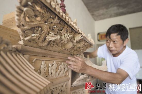谢树荣对自己的木雕作品总是一丝不苟，雕刻完后会仔细检查。汪成、周永冲/摄