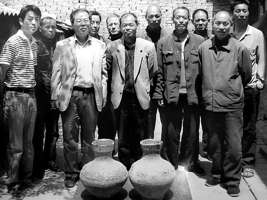 两个陶罐被文物局带走之前，挖宝农民要求和文物局、陶罐合影留念。