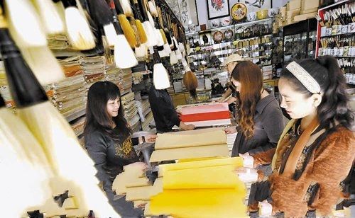 客户在老城历史文化街上的店铺里挑选宣纸。 