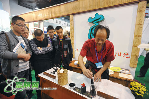 陈志炎在杭州文博会富阳展区前现场书法，挂在“门楣”上的就是他的竹雕作品《富春山居图》。