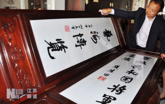 民间艺人谢惠强正在小心擦拭已经完成组装的百扇红木“将军书法”屏风中的部分屏风