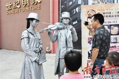 三乡古典家具文化节现场，涂了银漆的真人雕塑引来市民围观。 覃素玲 袁旺 摄