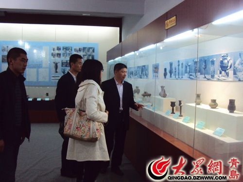 胶州市博物馆负责人王磊在为参观者介绍三里河遗址出土陶器。