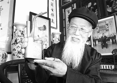 李赢向记者展示他收藏的一件铜烟袋。 张玉宇摄