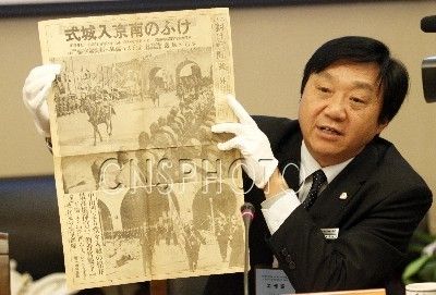 2011年12月13日，侵华日军南京大屠杀遇难同胞纪念馆馆长朱成山展示日本友人大东仁捐赠的1937年12月17日出版的朝日新闻号外“今日南京如城式”。 