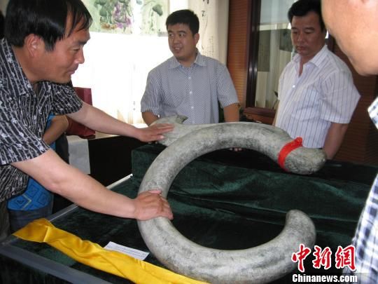  世界华人珠宝总商会龙宝文化研究所所长刘景玉捐赠的C字龙，引起现场来宾的极大兴趣。　田齐　摄