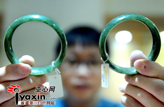 图为一位销售商给记者展示两只中档次得玛纳斯碧玉手镯。他说，玛纳斯碧玉的最大特点就是比和田碧玉的“黑点”要多，而这些黑点的主要成分为铁。亚心网记者 张万德 摄