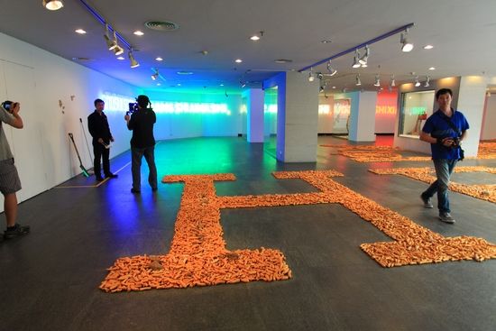 展厅内，1200斤“金狗屎”摆出极似爱马仕的LOGO，墙上的霓虹灯用拼音打出了“AIMASHISHIGOUSHI”的字样。