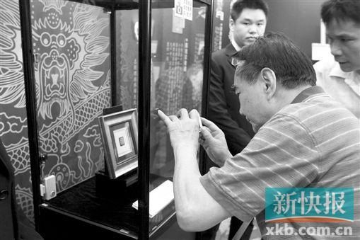 游客拿出手机拍摄价值500万元的“红印花小壹圆”邮票。 新快报记者 祝贺 摄