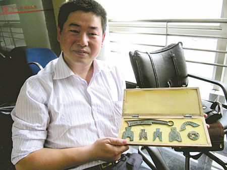 　图为王建明和他的“钱币宝贝”。(杨绪忠汪雯摄)
