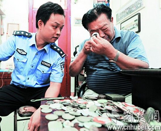 图为：专家协助民警对这些古钱币进行鉴定 记者佟建国摄