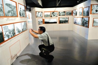 昨日，抗战纪念馆，一位观众观看展览照片，并用手机翻拍下来。新京报记者 吴江 摄