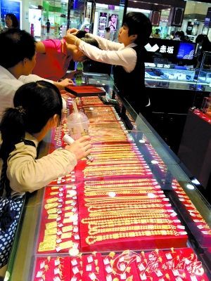 顾客在商场选购金饰。